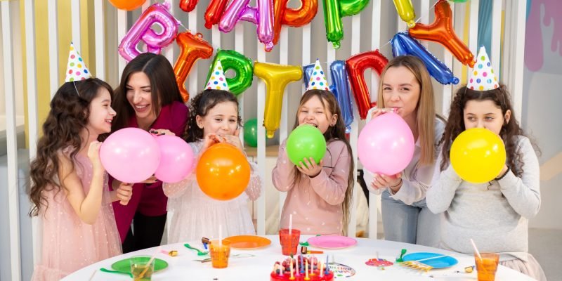 Group of children celebrate a children's birthday, have fun. Children and parents inflate balloons.