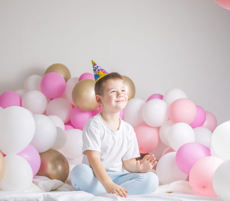 Little boy in white balloons . Small child with party balloons, celebration. Birthday, happiness, childhood, look.